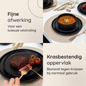 Zwarte borden met een biefstuk en tomaat, en een kom met soep.
