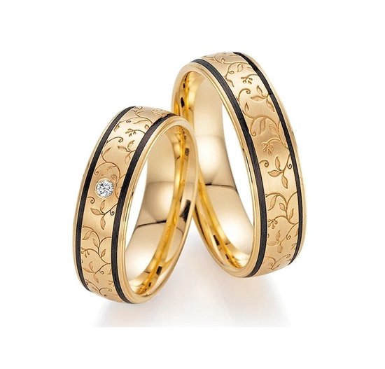 Gouden trouwringen met een zwart gravurepatroon van bladeren en één ring met een diamant.