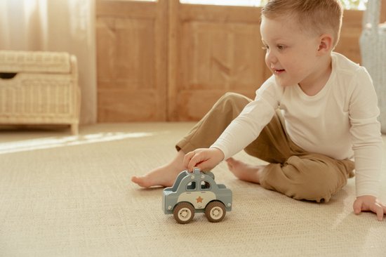Blauwe houten politieauto met ster, vastgehouden door handjes van een jongetje.