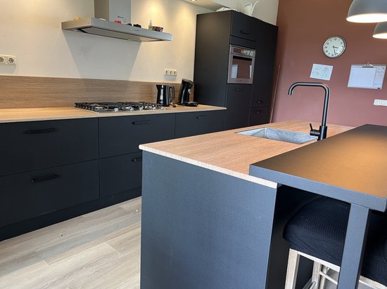 Moderne zwarte keuken met houten aanrechtblad en een kookeiland met gootsteen.