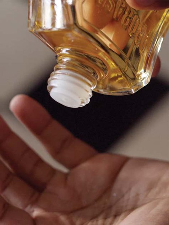 Gouden na scheerlotion wordt uit een Proraso fles in een hand gegoten.