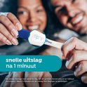 Een stel houdt een Clearblue zwangerschapstest vast. Snelle uitslag na 1 minuut.