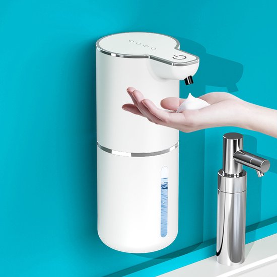 Witte automatische zeepdispenser geeft schuim af in een hand, met een zilveren kraan ernaast.