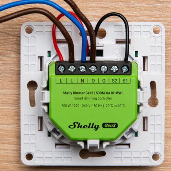 Groene Shelly Dimmer Gen3 slimme dimcontroller met schroefklemmen, gemonteerd op een witte basisplaat met bruine, blauwe en rode draden.