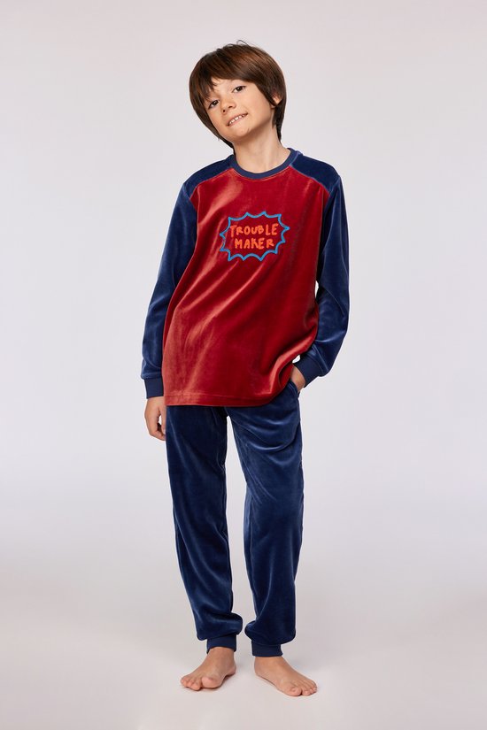 Garçon portant un pantalon de pyjama bleu marine en velours et un haut rouge avec l'inscription 'Trouble Maker'.