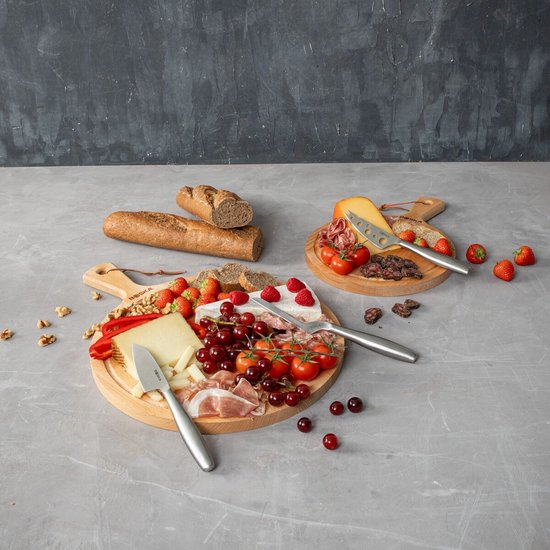 Deux planches de service en bois avec du fromage, de la charcuterie, des fruits et du pain. Une planche est garnie de brie, fraises et raisins. L'autre de fromage jeune, salami et tomates.