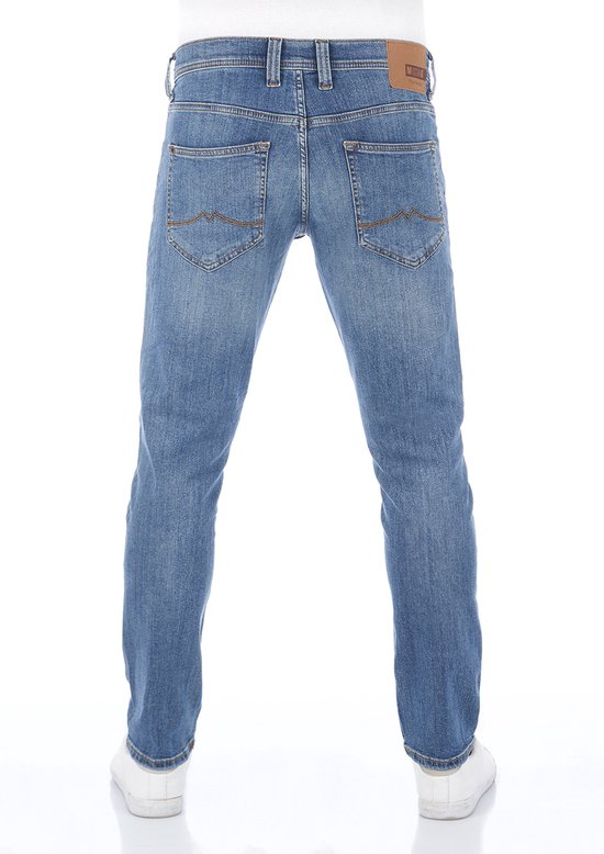 Achteraanzicht van een model in blauwe Mustang jeans met leren label en witte sneakers.