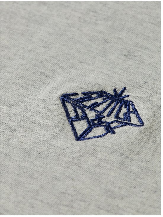 Detail van het donkerblauwe geborduurde logo op een lichtgrijs T-shirt.