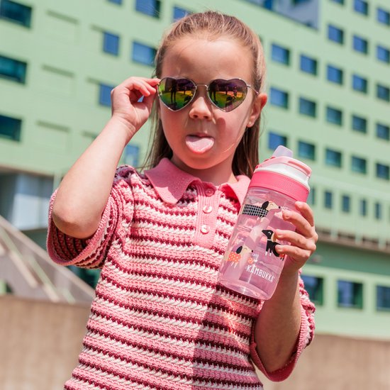 Une fille avec des lunettes de soleil en forme de cœur et la langue tirée, tient une bouteille Kambukka rose avec un imprimé de chiens.