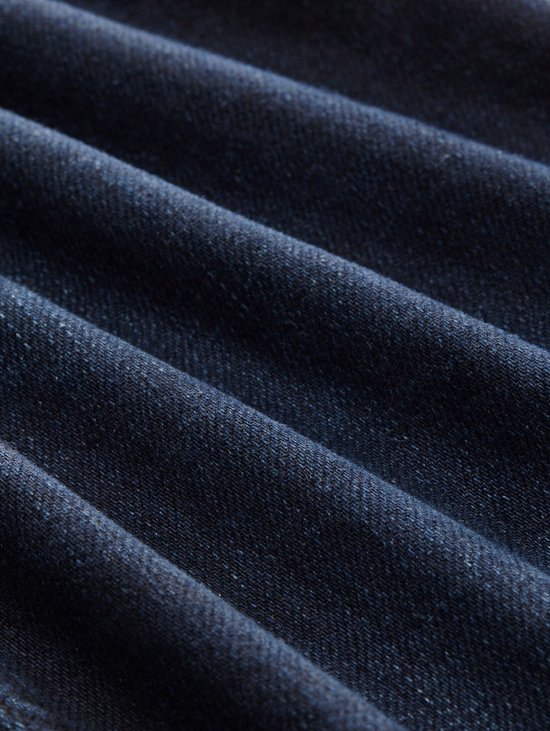 Close-up van de textuur van donkerblauwe denim stof met vouwen.