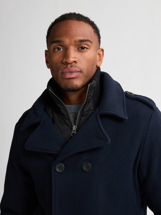 Close-up van een man met donkerblauwe peacoat met dubbele rij knopen en staande ribkraag.