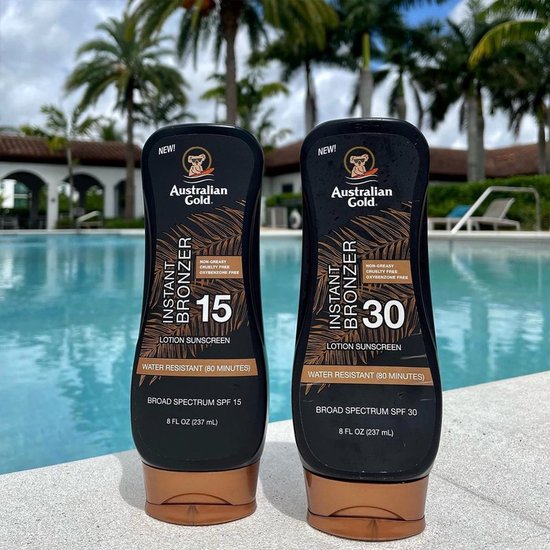 Twee flessen Australian Gold Instant Bronzer SPF 15 en SPF 30 lotion naast een zwembad.