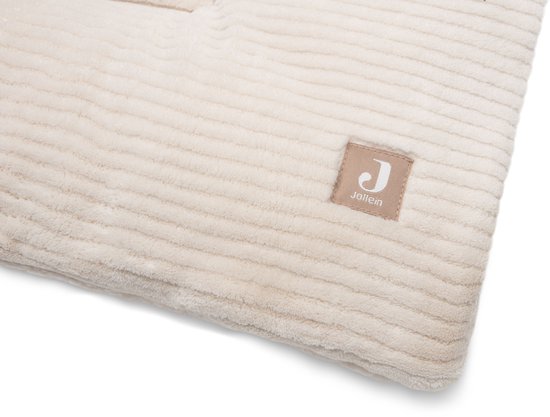 Close-up van een lichtbeige boxkleed met ribbelpatroon, met een label met het Jollein logo.