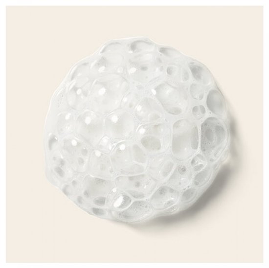 Een klontje wit schuim met veel kleine bubbels op een crèmekleurige achtergrond.