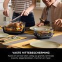 Mensen snijden en serveren een geroosterde kip en gegrilde asperges aan tafel.