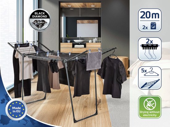 Étendoir noir avec vêtements, serviette et cintres dans une salle de bain.