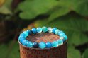 Armband met blauwe en witte agaatkralen op een verroeste metalen paal.