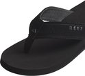 Detailopname van een zwarte Reef slipper. Focus op de band met Reef logo en textuur.