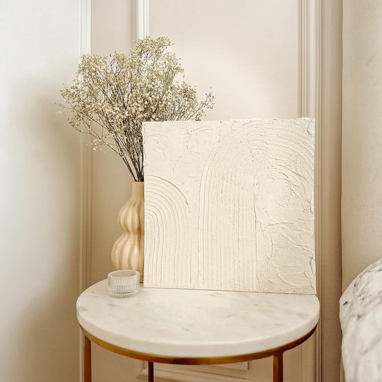 Een beige textuurkunstwerk met regenboogpatroon en een vaas met bloemen op een marmeren tafel.