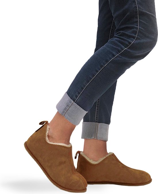 Bruine wollen pantoffels met witte vachtvoering, gedragen met jeans.