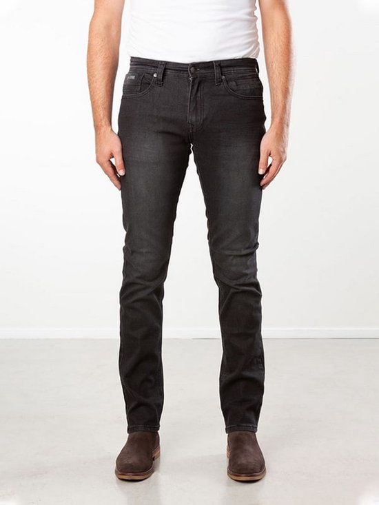 Model in een zwarte, slim fit stretch spijkerbroek met een lichte wassing en bruine schoenen.