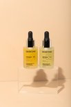 Twee glazen flesjes: SKINONE vitamine C serum (geel) en SKINONE retinol serum (lichtgeel).