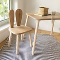 Houten kinderstoel met konijnenoren en een bijpassende tafel, met een mandje en boek erop.