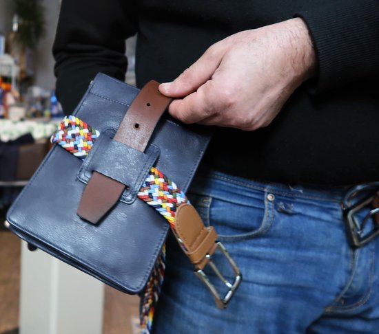 Man met jeans en zwarte trui, donkerblauwe leren tas met gekleurde riem.