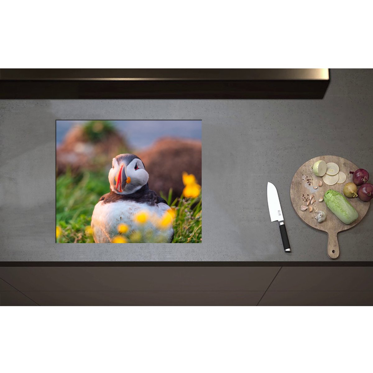 Inductieplaat Beschermer - Aankijkende Papegaaiduiker Vogel in Landschap met Gele Bloemetjes - 59x50 cm - 2 mm Dik - Inductie Beschermer - Bescherming Inductiekookplaat - Kookplaat Beschermer van Zwart Vinyl