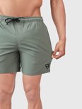 Détail d'un short de bain vert vintage avec logo noir sur la jambe gauche.