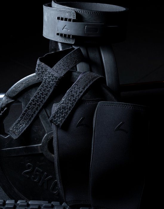 Zwarte lifting riem, polsbanden en lifting straps met honingraatpatroon, op een gewichtschijf.