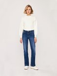 Vrouw in een donkerblauwe LTB flared jeans en witte trui.