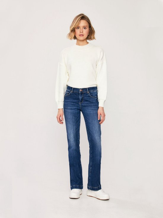Vrouw in een donkerblauwe LTB flared jeans en witte trui.