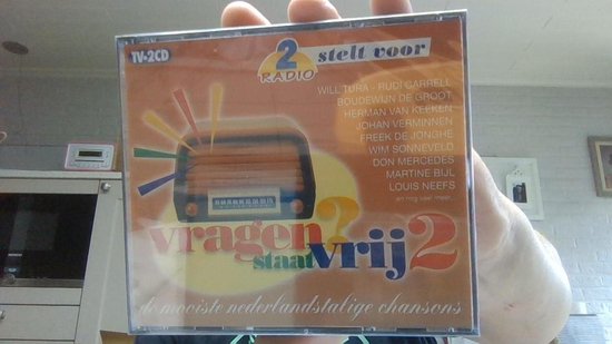 CD-hoes met de titel 'Vragen Staat Vrij 2', oranje met retro radio en artiestenlijst.