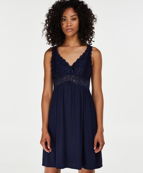 Vrouw met donkerblauwe slipdress met V-hals en kanten details.