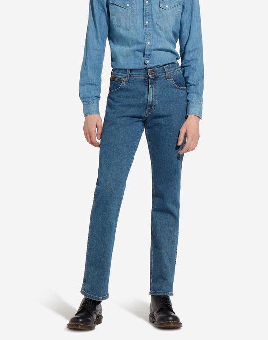 Model in blauwe spijkerbroek en denim overhemd, zwarte schoenen.