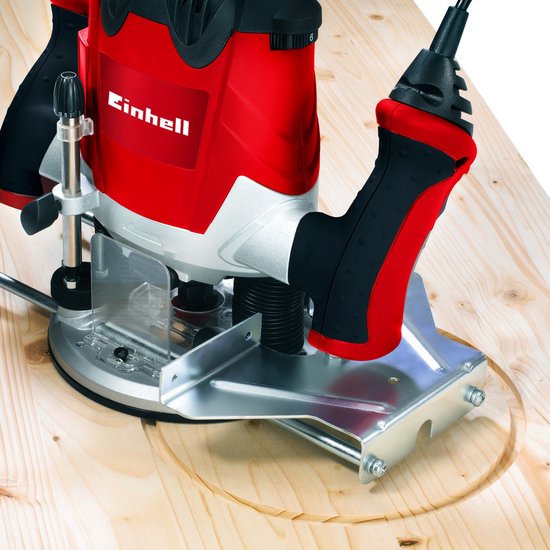 Einhell bovenfrees met rode en zilveren behuizing, zaag diep in een houten plank.