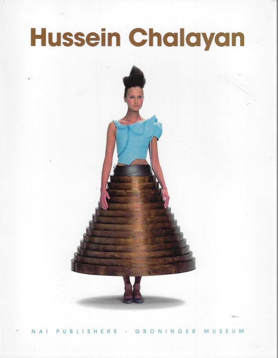 Model in lichtblauwe top met asymmetrische mouw en een rok van gestapelde houten schijven, met de tekst "Hussein Chalayan".