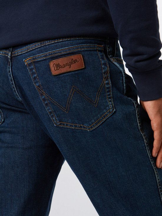 Close-up van de achterkant van jeans met een bruine leren Wrangler-patch en de kenmerkende 'W'-stiksels.