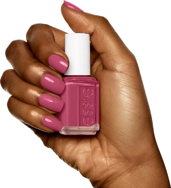 Hand met donkere huidskleur die een flesje Essie nagellak vasthoudt. Nagels gelakt in roze.