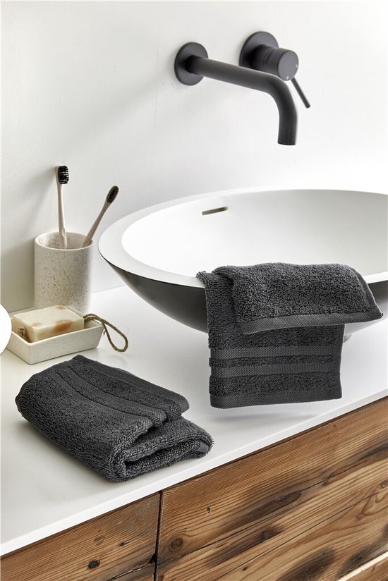 Serviettes anthracite près d'un lavabo, avec du savon et des brosses à dents.