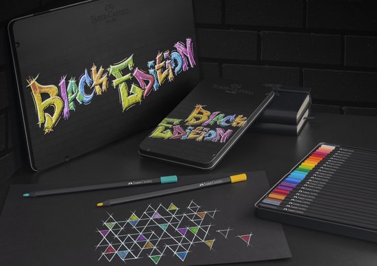 Zwarte etuis met 'Black Edition' graffiti, notitieboek, zwarte potloden en papier met tekening.
