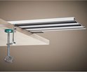Grijze C-klem met groene schijf klemt een metalen profiel op een houten plank.
