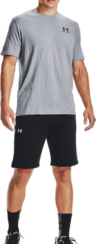 Man met grijze Under Armour t-shirt en zwarte korte broek. Grijs t-shirt met zwart Under Armour logo links op de borst.