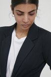 Close-up van een vrouw met donker haar die een marineblauwe blazer draagt met een witte t-shirt eronder.