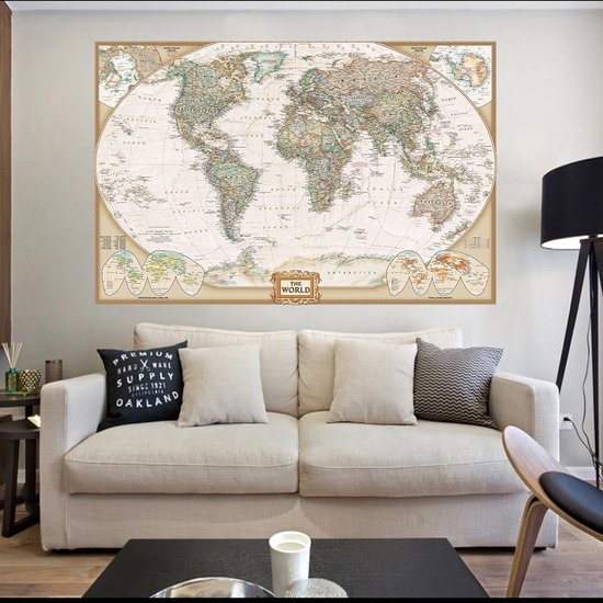 Gedetailleerde wereldkaart in vintage stijl, landkleuren, omringende inzetkaarten, gouden rand, boven een bank met sierkussens.