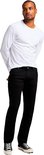 Man met witte longsleeve en zwarte jeans, staand.