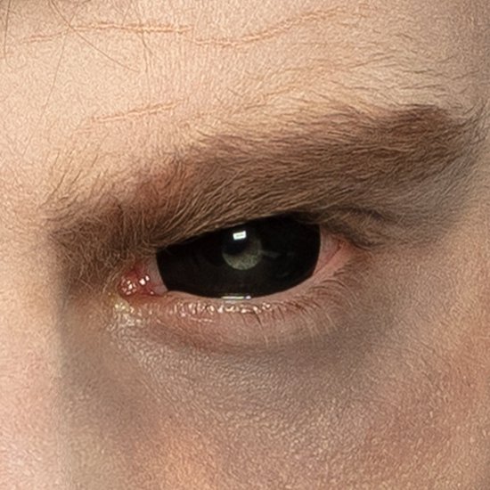 Zwarte scleralens die het oog bedekt, met bruine wenkbrauw en huidplooien.