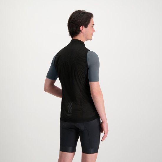 Man, van achteren gezien, met zwart fietsjack over grijs shirt, zwarte fietsbroek.