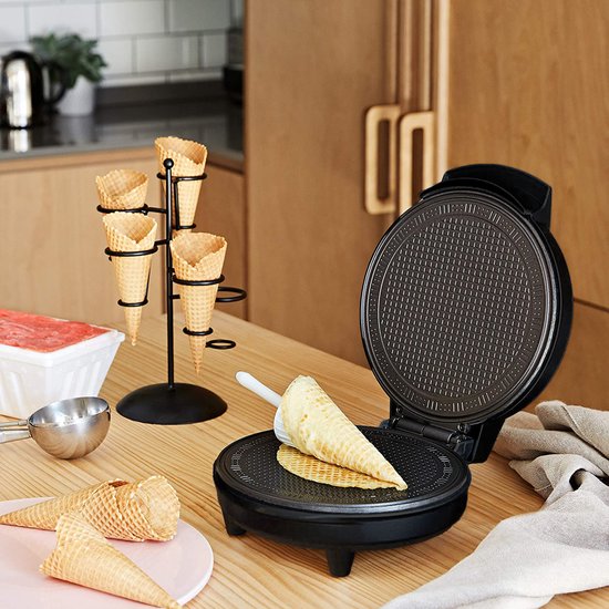 Open zwart wafelijzer op een houten aanrecht met wafelhoorntjes, schepje en ijshoornvorm.